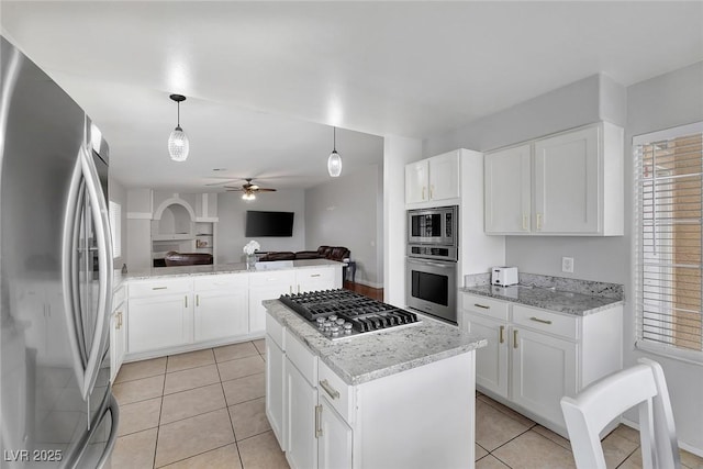 kitchen featuring light stone counters, light tile patterned floors, a kitchen island, appliances with stainless steel finishes, and open floor plan