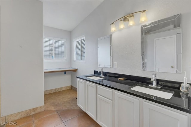 full bath with a sink, baseboards, double vanity, and tile patterned flooring