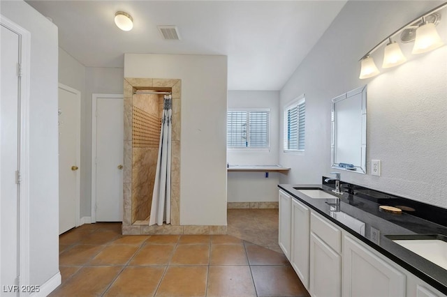 full bathroom featuring tile patterned floors, visible vents, a sink, baseboards, and tiled shower