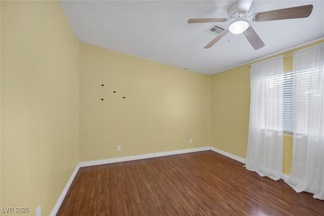 spare room with ceiling fan, visible vents, baseboards, and wood finished floors