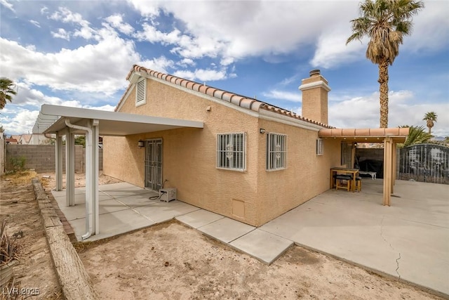 back of property with stucco siding, a patio, and fence