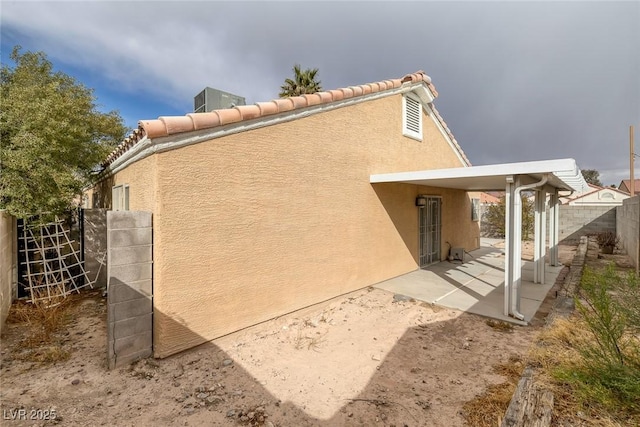 view of property exterior featuring stucco siding, a patio area, and fence