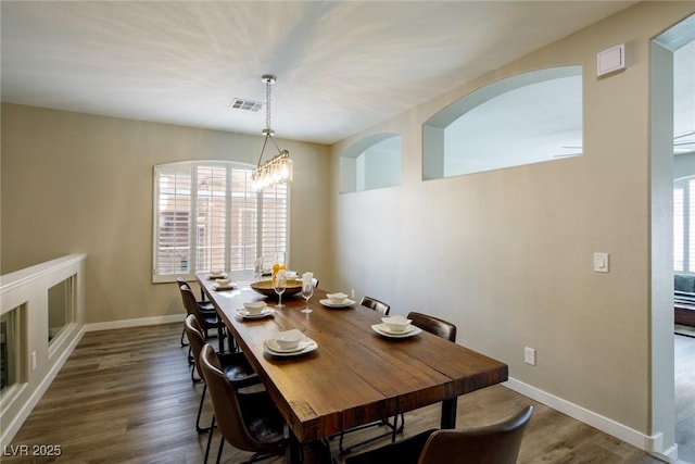 dining room featuring dark wood finished floors, a notable chandelier, baseboards, and visible vents