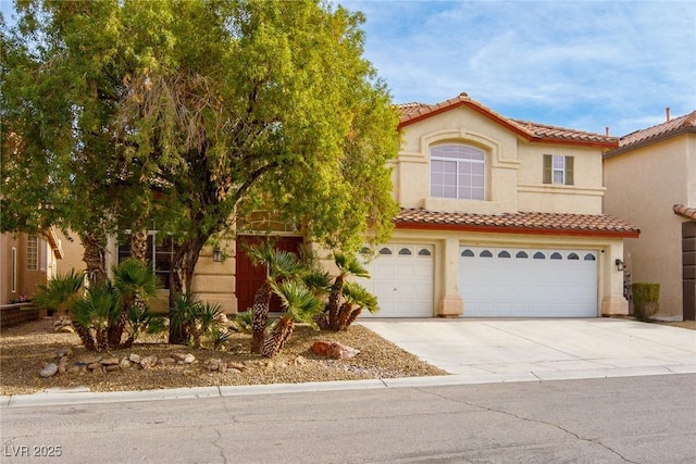 mediterranean / spanish house with a tile roof, concrete driveway, a garage, and stucco siding