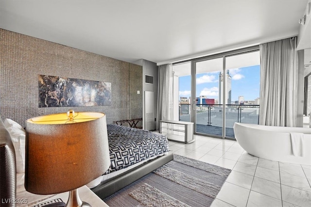 tiled bedroom with access to exterior, visible vents, an accent wall, floor to ceiling windows, and a view of city