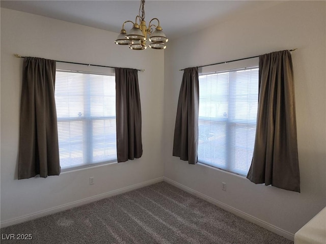 carpeted empty room featuring baseboards, plenty of natural light, and an inviting chandelier