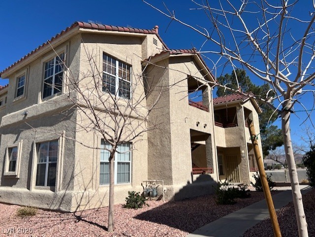 view of side of property with a tile roof and stucco siding