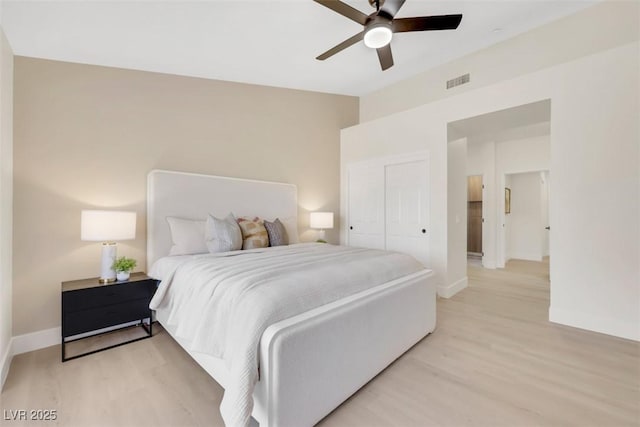 bedroom featuring light wood finished floors, visible vents, baseboards, a closet, and a ceiling fan