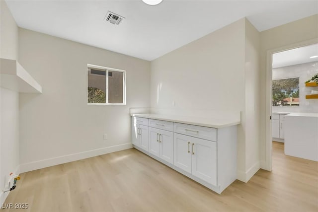 interior space with light wood-style floors, visible vents, and baseboards