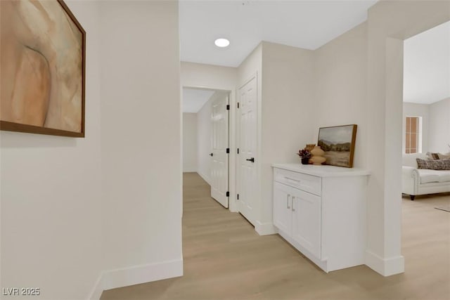 hall featuring baseboards and light wood-style flooring