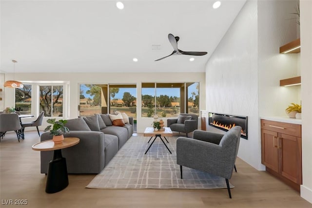 living room featuring recessed lighting, light wood-type flooring, a large fireplace, and lofted ceiling