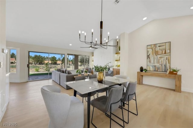 dining space with light wood-style flooring, baseboards, lofted ceiling, and an inviting chandelier