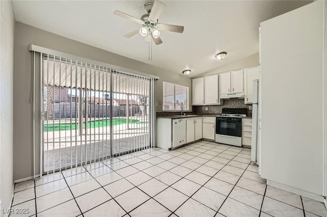 kitchen featuring a sink, dark countertops, gas range oven, white dishwasher, and decorative backsplash