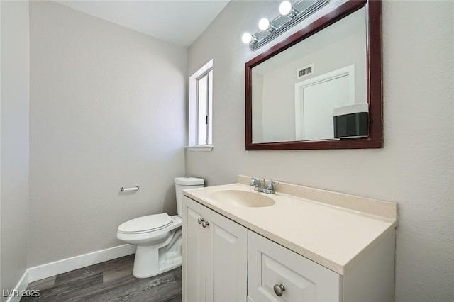 bathroom featuring vanity, wood finished floors, baseboards, visible vents, and toilet