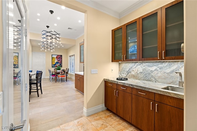 kitchen featuring glass insert cabinets, crown molding, baseboards, decorative backsplash, and a sink