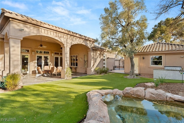 back of house featuring a yard, stucco siding, a ceiling fan, and a patio