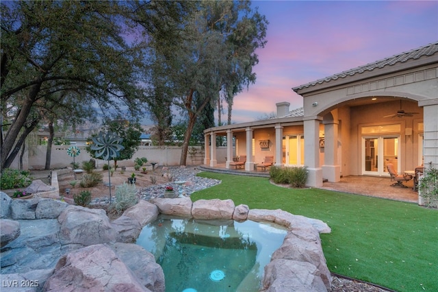 exterior space featuring a patio, a lawn, a ceiling fan, and fence