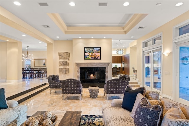 living room featuring visible vents, baseboards, a tray ceiling, a premium fireplace, and recessed lighting