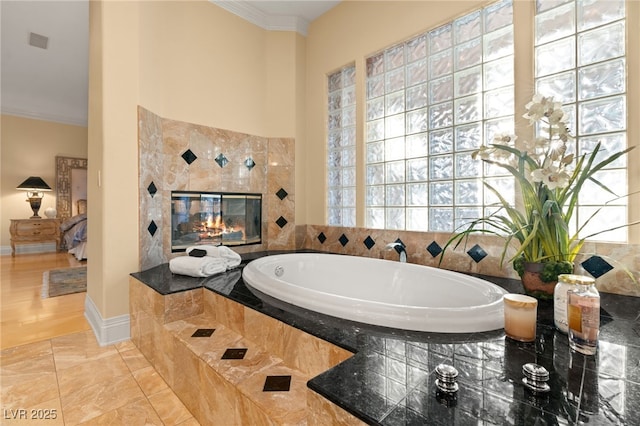 full bathroom with visible vents, baseboards, a tiled fireplace, ornamental molding, and a bath