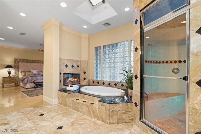 ensuite bathroom featuring a shower stall, crown molding, a fireplace, a skylight, and a bath