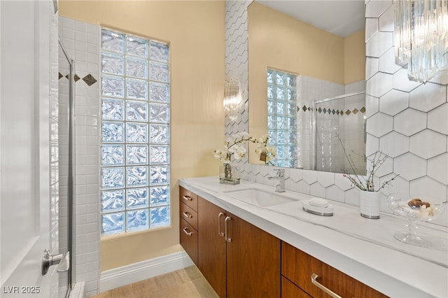 bathroom featuring vanity, a shower stall, and backsplash