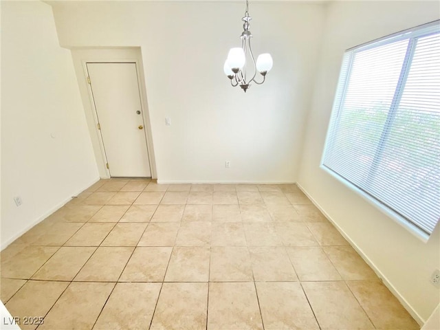 spare room with light tile patterned flooring, baseboards, and an inviting chandelier