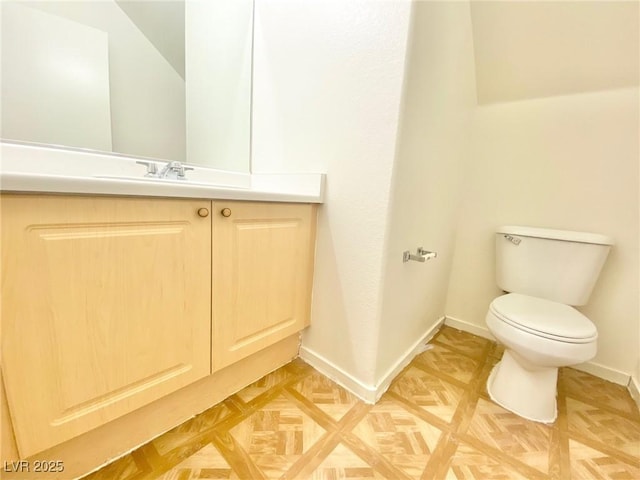 bathroom with toilet, vanity, and baseboards