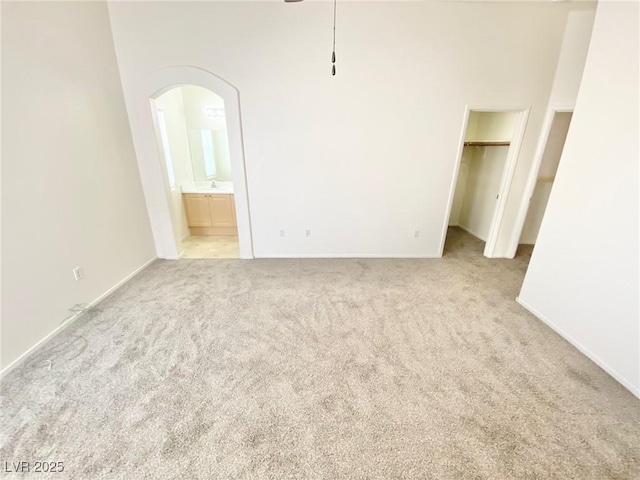 empty room with carpet, arched walkways, a towering ceiling, and a sink