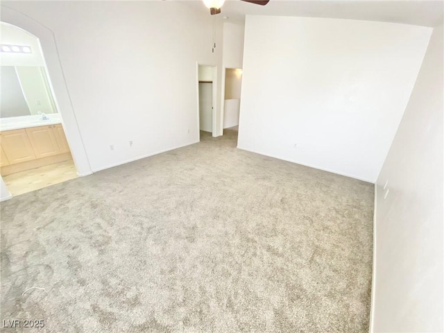 carpeted empty room with a sink, ceiling fan, and vaulted ceiling