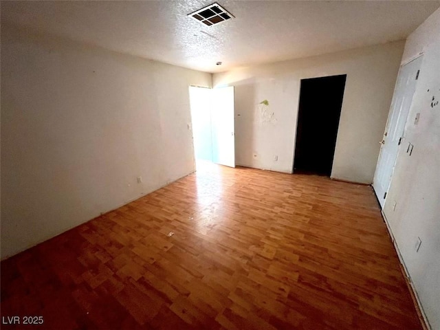 interior space featuring wood finished floors, visible vents, and a textured ceiling