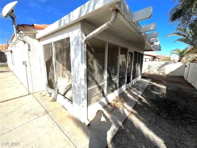 view of side of property featuring a fenced backyard and a sunroom