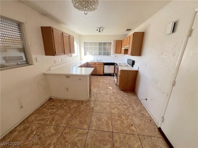 kitchen with a sink, a textured ceiling, gas stove, a peninsula, and white dishwasher