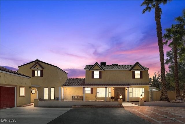 view of front of home featuring a tiled roof, fence, driveway, and stucco siding