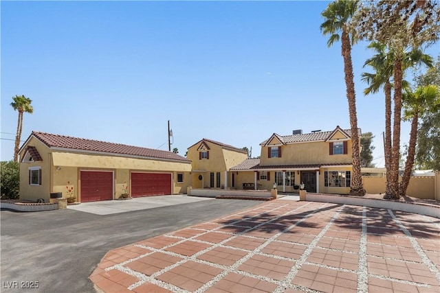 view of front of home with stucco siding, a tiled roof, an attached garage, and decorative driveway