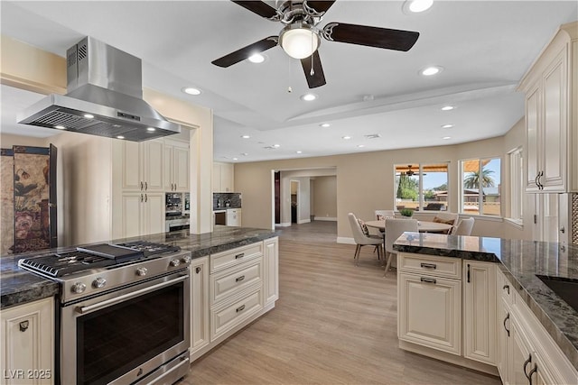 kitchen with open floor plan, stainless steel range with gas stovetop, light wood-style floors, island range hood, and cream cabinetry