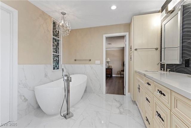 full bath featuring marble finish floor, recessed lighting, connected bathroom, a freestanding bath, and vanity