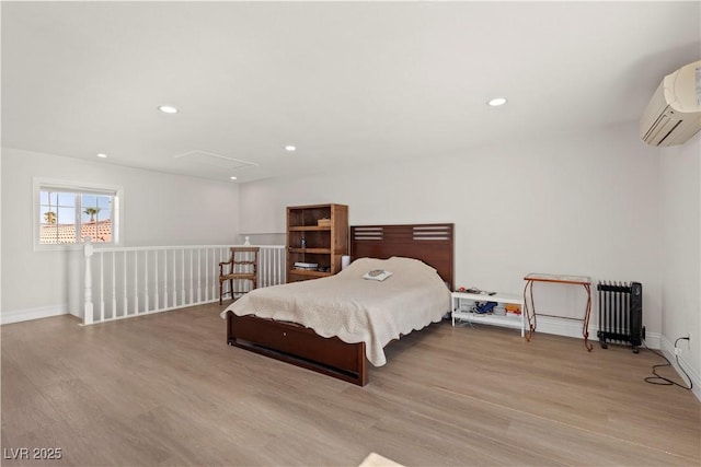 bedroom featuring recessed lighting, attic access, wood finished floors, and a wall unit AC