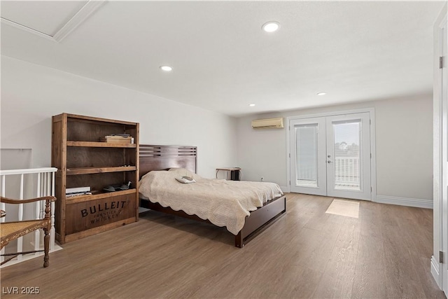 bedroom with access to outside, wood finished floors, a wall unit AC, recessed lighting, and french doors