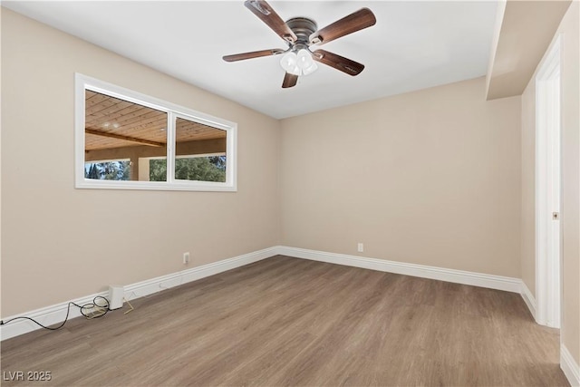 spare room featuring a ceiling fan, baseboards, and wood finished floors