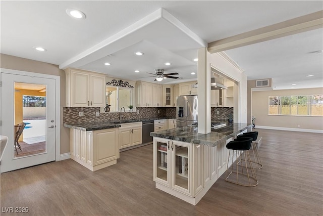 kitchen featuring visible vents, cream cabinetry, a sink, appliances with stainless steel finishes, and glass insert cabinets