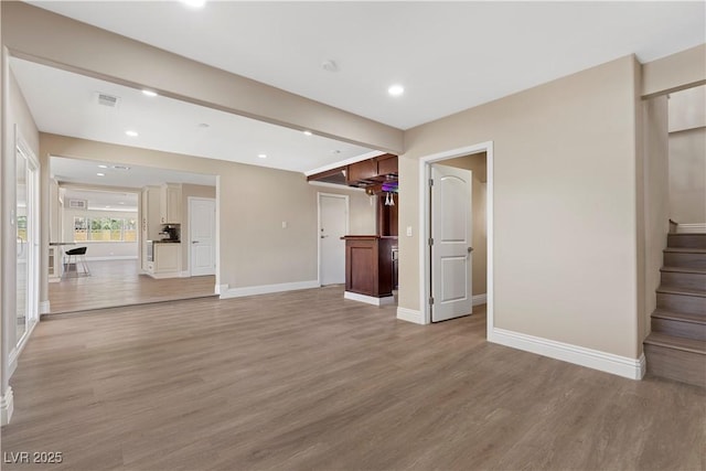 unfurnished living room with stairs, light wood-style flooring, recessed lighting, and baseboards