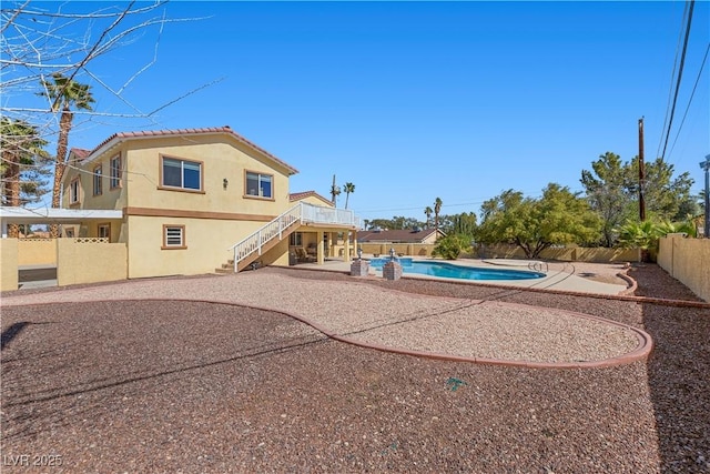 back of house featuring a patio, stairway, a fenced in pool, a fenced backyard, and stucco siding