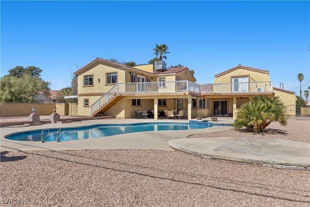 rear view of house featuring fence, stucco siding, an outdoor hangout area, a balcony, and a patio area