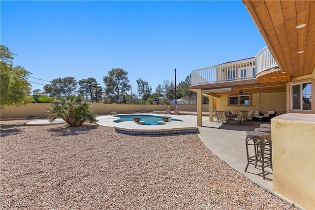 view of yard featuring outdoor dining space, a patio, a fenced backyard, a fenced in pool, and a balcony