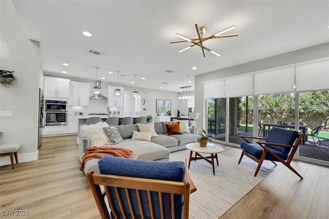 living area with visible vents, recessed lighting, light wood-style floors, an inviting chandelier, and baseboards