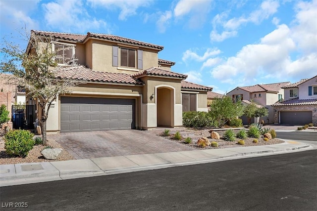 mediterranean / spanish-style house featuring a tile roof, decorative driveway, a garage, and stucco siding