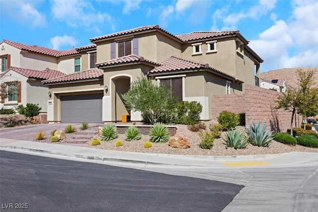 mediterranean / spanish-style home featuring stucco siding, driveway, and a garage