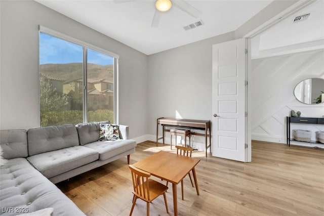 living room featuring light wood finished floors, visible vents, and a ceiling fan