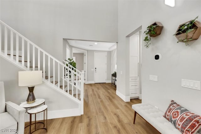 foyer entrance with stairway, wood finished floors, and baseboards