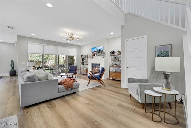 living room featuring visible vents, wood finished floors, a glass covered fireplace, recessed lighting, and baseboards